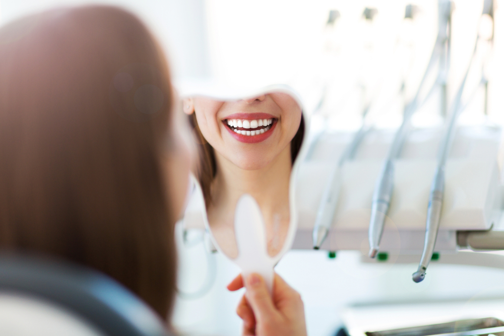 woman looking at smile after periodontist treatment